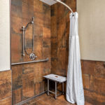 roll-in shower with seat, grab bars, and adjustable shower head