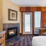 guest room with one king bed and fireplace and balcony