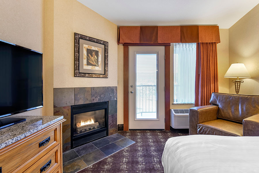 guest room with one king bed and fireplace and balcony